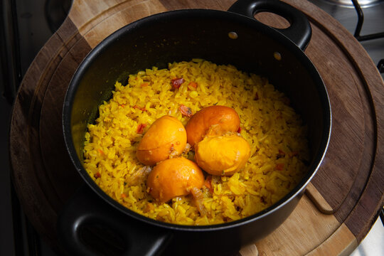 Uma panela preta com arroz com pequi sobre uma t&aacute;bua de madeira. Um prato t&iacute;pico brasileiro.