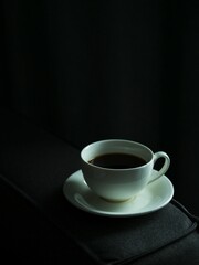 Vertical high angle shot of a white instant coffee mug on a black couch