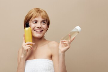a happy, friendly woman with clean skin, stands on a beige background and advertises jars of...