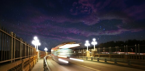 Panoramic long exposure of a bus driving trough a road during night under a starry purple sky