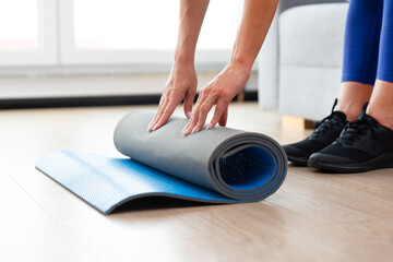 Fototapeta premium Woman folding mat, workout at home concept