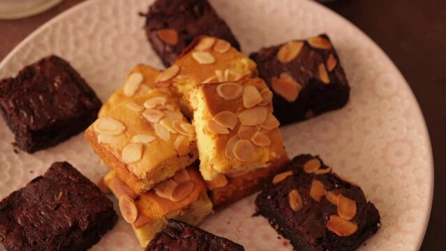 A tilt down shot from glass of coffee to a plate of blondes and brownies.