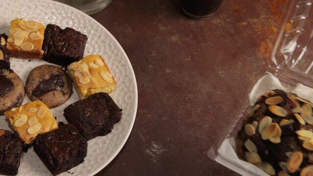 Banana bread, blondes, and brownies are presented on a round wooden table.