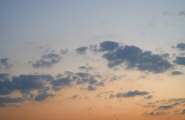 The blue sky is orange and the clouds are soft when the sun is about to set.