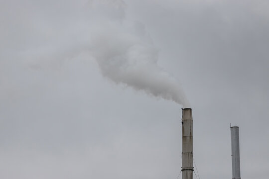 white smoke from meatl chimney of the industry factory with grey sky background.  air pollution.