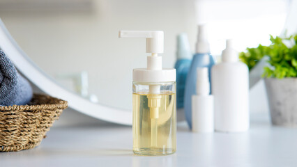 Liquid soap bottle, gray towel on basket in bathroom. Hygiene and healthy life concept. Close up, selective focus
