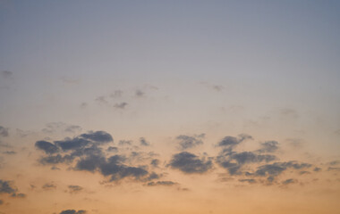 The blue sky is orange and the clouds are soft when the sun is about to set.