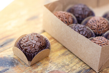 brigadeiro on a wooden table, with a box of brigadiers. Brazilian traditional sweet.