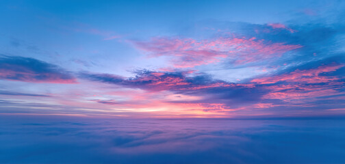 Panoramic, aerial view of sky between two layers of clouds in pink, blue and violet colors.  After sunset sky.