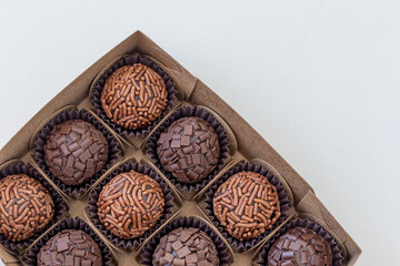 Box with several brigadeiros lined up on white background. Brazilian traditional sweet.