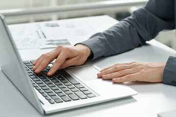 Close-up of young secretary typing on computer keyboard while working at table at office