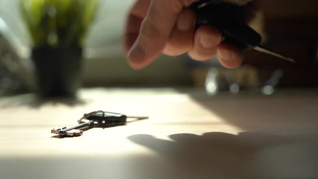 Hand Takes Remote Control Car Keys And Apartment Keys From The Table