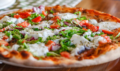 Turkish pizza with lamb tomatoes lettuce onion and yogurt on wooden table, side view, selective focus