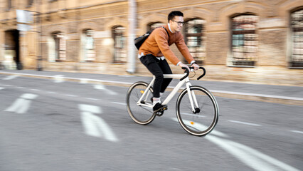 Blurry photo Photography in motion. A bicyclist rides a bicycle to work in the city. Ecological...