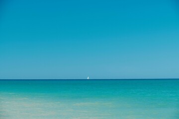 Fototapeta na wymiar Minimalistic seascape with a sailboat in the horizon