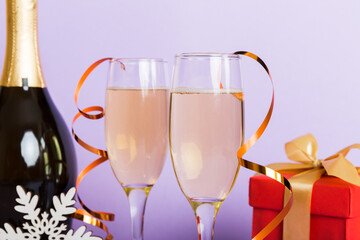 Champagne bottle with confetti, glasses and christmas decor on colored holiday background. Flat lay New Year decorations