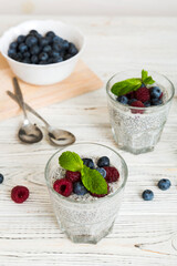 Healthy breakfast or morning with chia seeds vanilla pudding raspberry and blueberry berries on table background, vegetarian food, diet and health concept. Chia pudding with raspberry and blueberry