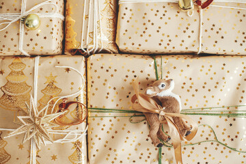 Stylish christmas gifts flat lay. Modern christmas gift boxes with deer toy, golden star, bell, festive paper and ornaments composition. Merry Christmas and Happy Holidays! Presents for child