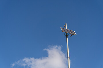 Small solar panel installed on a metal pole, against a blue cloudy sky