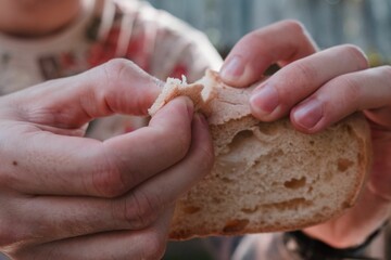 Closeup shot of a person pulling of a piece from a bread slice