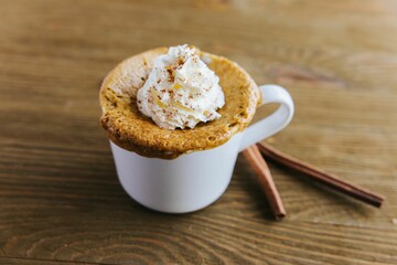 Closeup of an appetizing Pumpkin Spice Mug Cake surrounded by cinnamon rolls on the table