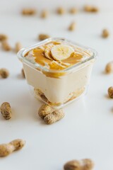 Vertical closeup of a Peanut Butter Banana Mousse in a bowl surrounded by peanuts