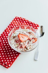 Vertical shot of appetizing Oats with Strawberries in a bowl with a red decorative napkin