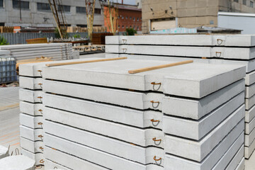 Reinforced concrete road slab for temporary and permanent roads, stacked in a factory warehouse.