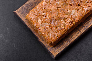 Tasty meat brawn or roll on a wooden cutting board with spices and herbs