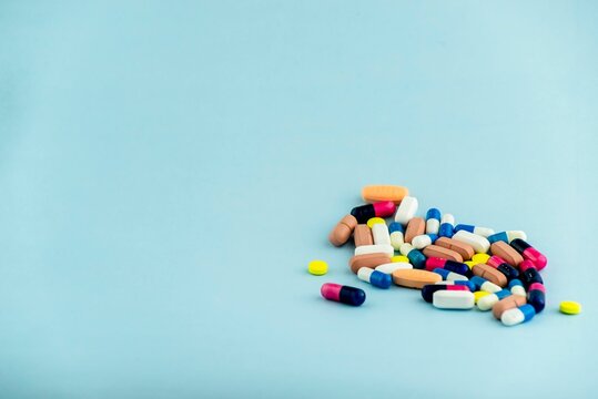 Pile of colorful medical pills and capsules isolated on a blue background