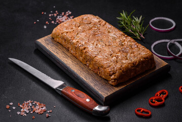 Tasty meat brawn or roll on a wooden cutting board with spices and herbs