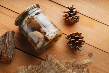 Pickled mushrooms on rustic wooden table. Homemade preserves in a glass jar. Copy space