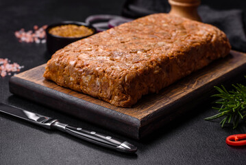 Tasty meat brawn or roll on a wooden cutting board with spices and herbs