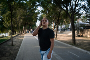 Portrait of a young non-binary person of Latin American origin looking at the camera while posing standing in the street. Concept of ethnic and gender diversity.