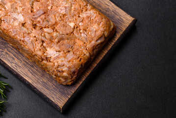 Tasty meat brawn or roll on a wooden cutting board with spices and herbs