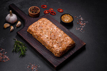 Tasty meat brawn or roll on a wooden cutting board with spices and herbs