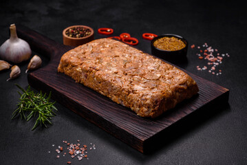 Tasty meat brawn or roll on a wooden cutting board with spices and herbs