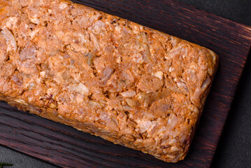 Tasty meat brawn or roll on a wooden cutting board with spices and herbs