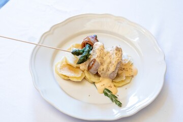 White plate with served beef with cheese sauce and asparagus