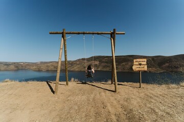 Caucasian female swinging on the sandy of Lagos do Sabor in Miradouro de Sao Lourenco, Portugal