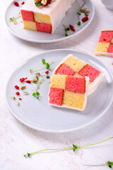 Slices of Battenberg cake, traditional British dessert with two-colored sponge cake wrapped in marzipan, on white table