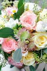 Vertical closeup shot of a beautiful bouquet of vibrant pink, yellow and white roses at a wedding