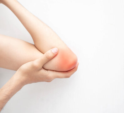 Lesion de codo de un joven hombre caucasico delgado sobre un fondo blanco enrojecido por un traumatismo musculoesqueletico 