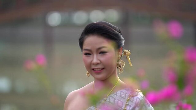 A woman in a traditional Thai costumes is walking in the garden while being taken a portrait photo shooting.