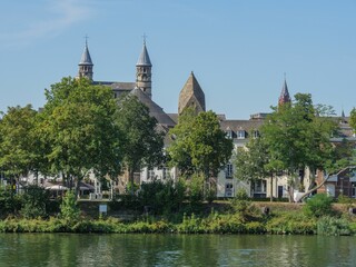 Fototapeta na wymiar Beautiful view of the Maas river surrounded by trees and old buildings in Maastricht, Netherlands.