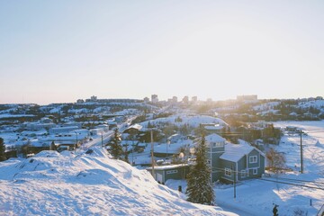 Obraz premium Winter landscape in small village with pine trees, hills and residential houses covered with snow