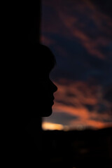 Dark silhouette of the face of a young woman during an incredible sunset
