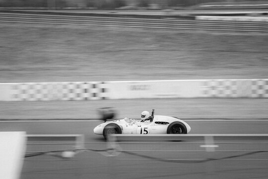 Grayscale shot of a historic formula car racing on a circuit.