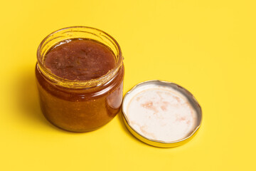 Glass jar of homemade fig jam on a yellow background