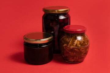 Jars of honey and jams on red background